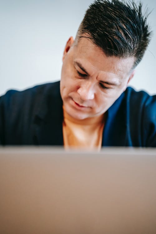 使用macbook的蓝色圆领衬衫的男人 · 免费素材图片