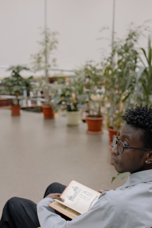 白色礼服衬衣佩带的眼镜的人阅读书 · 免费素材图片