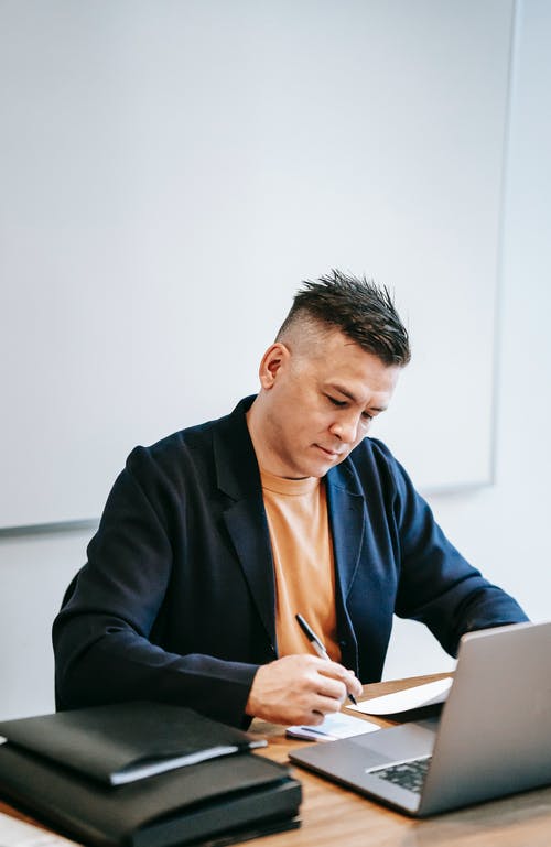 黑色西装外套的人使用银色ipad · 免费素材图片