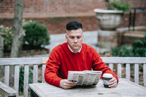 红色毛衣阅读报纸的人 · 免费素材图片