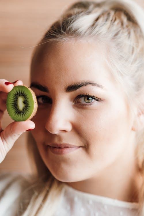 女人抱着绿色的圆形水果 · 免费素材图片