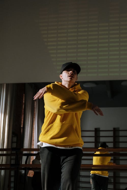 站在棕色的木桌附近的黄色衬衫的男人 · 免费素材图片