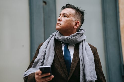 拿着黑色智能手机的黑色西装外套的男人 · 免费素材图片