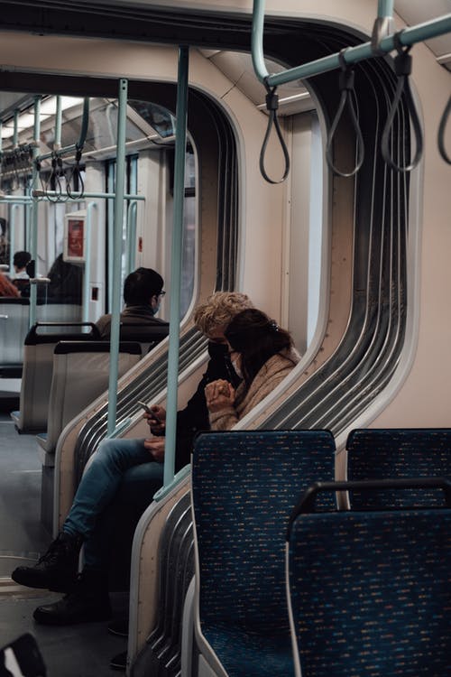人们坐在蓝色和灰色的火车座位上 · 免费素材图片