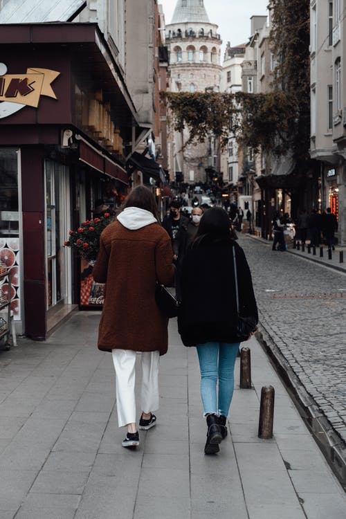 黑色外套和白色的裤子，在人行道上行走的女人 · 免费素材图片