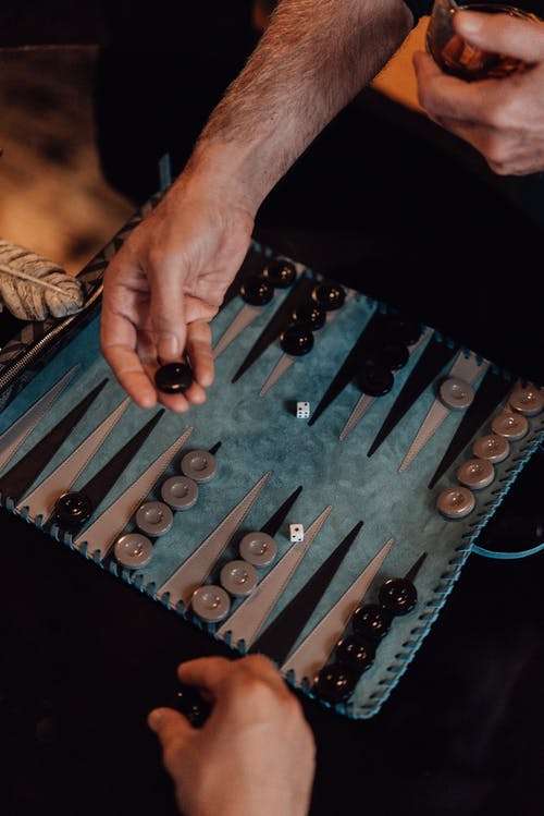 拿着黑色和银色国际象棋棋子的人 · 免费素材图片