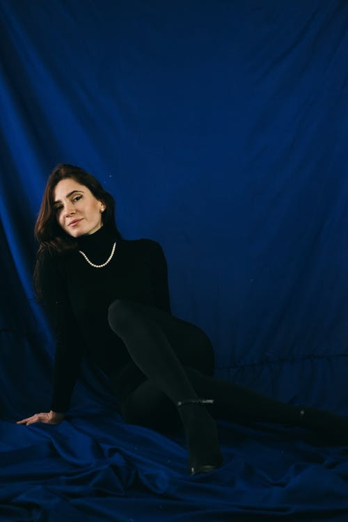 黑色长袖衬衫和黑色的裤子，坐在蓝色纺织上的女人 · 免费素材图片