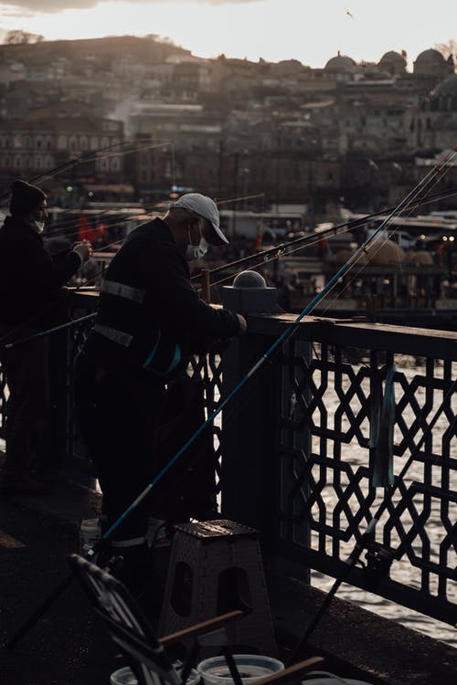 黑夹克和白帽子站在桥上的男人 · 免费素材图片