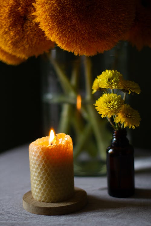 点燃蜡烛旁边的黄色花 · 免费素材图片