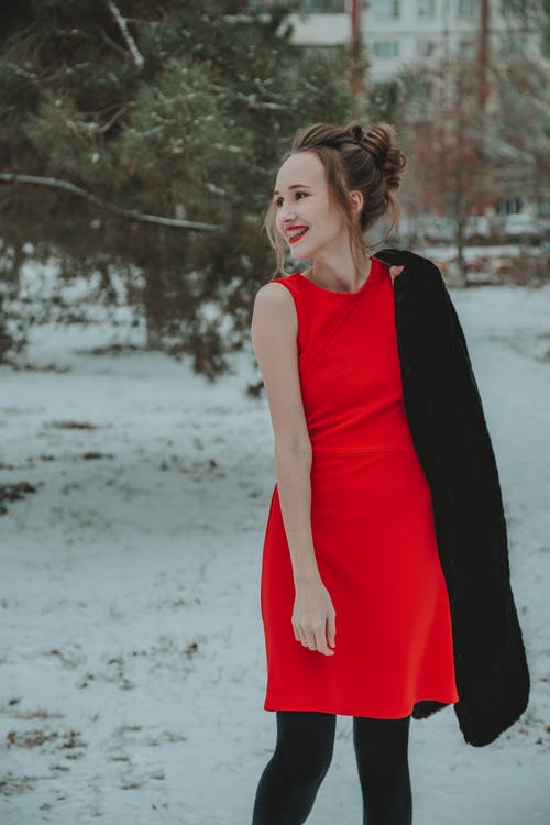红色无袖连衣裙站在雪地上的女人 · 免费素材图片