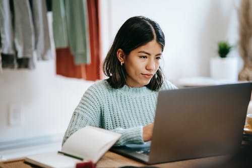 使用macbook的灰色毛衣的女人 · 免费素材图片