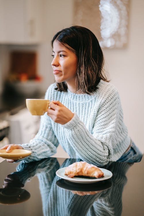 拿着白色陶瓷杯子的白色针织毛衫的女人 · 免费素材图片