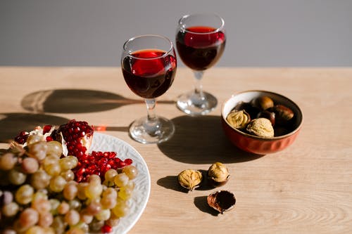 在棕色木制的桌子上的透明酒杯中的红酒 · 免费素材图片