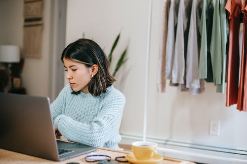 使用macbook Air的白色针织毛衣的女人 · 免费素材图片