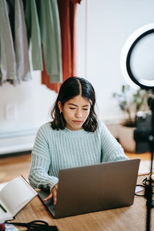 使用macbook Air的白色针织毛衣的女人 · 免费素材图片