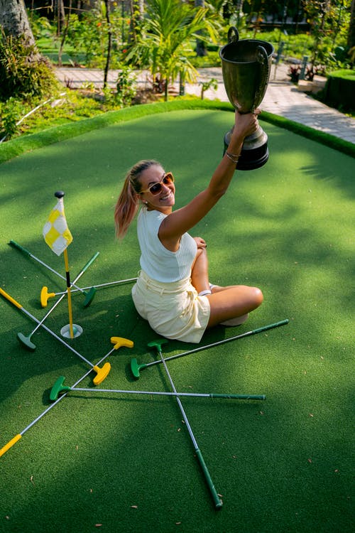 白衬衫和黄色短裤坐在绿草地上的女人 · 免费素材图片