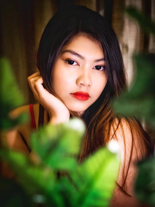 拿着绿色的树叶的红色唇膏的女人 · 免费素材图片