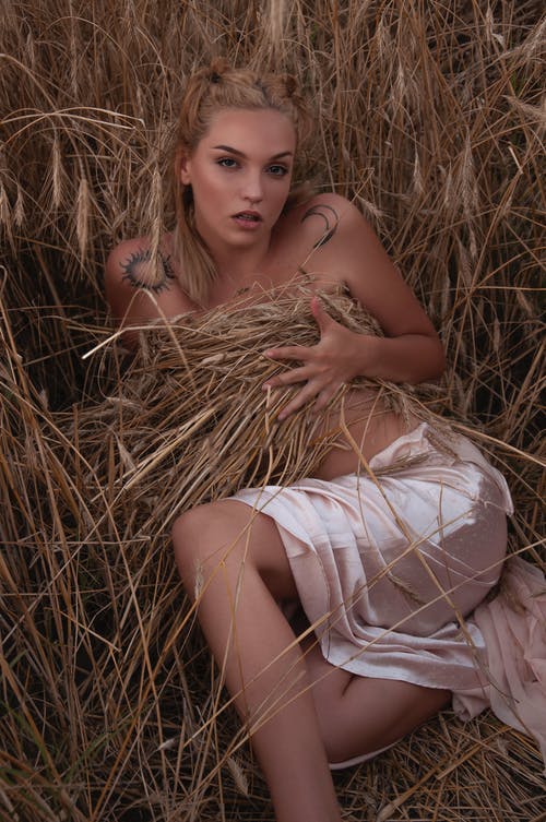 躺在棕色草地上的白色无袖连衣裙的女人 · 免费素材图片