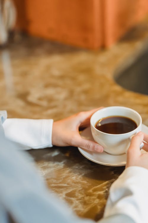 拿着白色陶瓷茶杯的人在白色陶瓷茶碟 · 免费素材图片