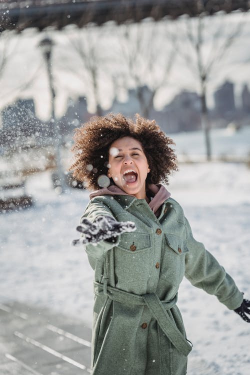 站在大雪覆盖地面上的绿色外套的女人 · 免费素材图片