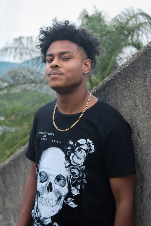 黑色和白色的圆领t恤站在灰色的混凝土墙旁边的女人 · 免费素材图片