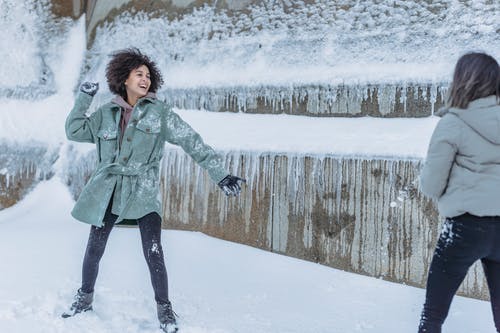 穿绿色外套和黑色的裤子，站在积雪的地面上的女人 · 免费素材图片