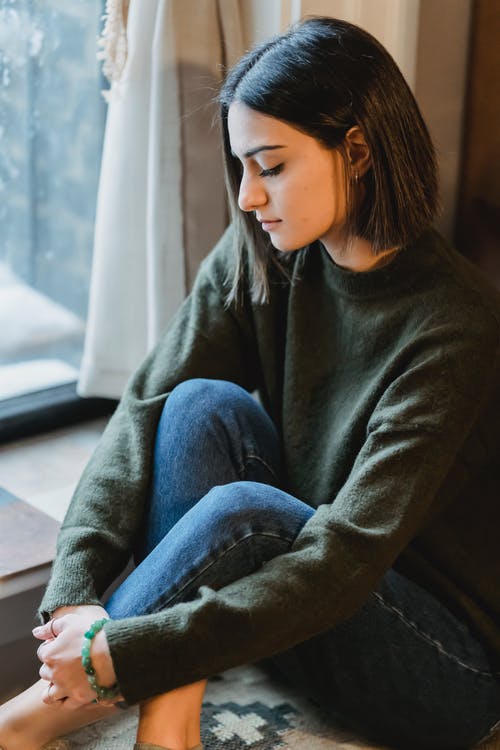 黑色毛衣和蓝色牛仔牛仔裤，坐在棕色的沙发上的女人 · 免费素材图片