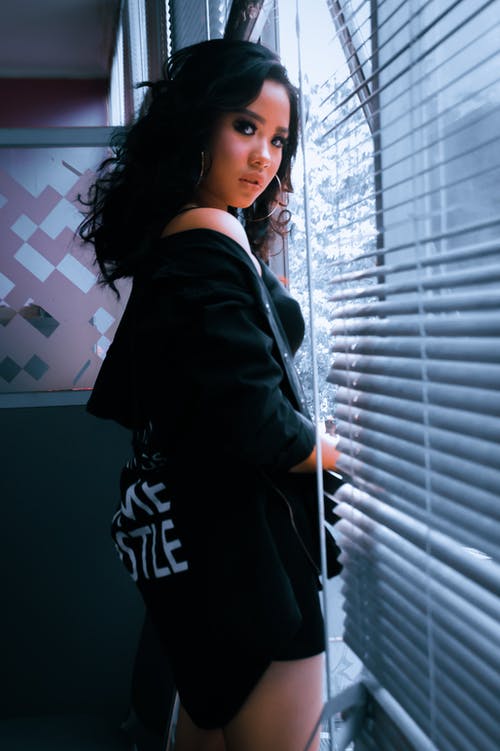 站在窗口附近的黑夹克的女人 · 免费素材图片