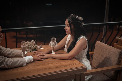 白色无袖连衣裙坐在棕色木椅上的女人 · 免费素材图片