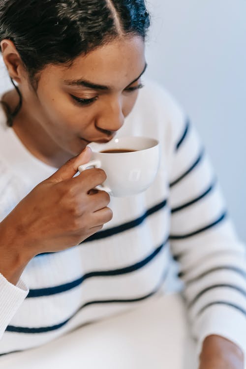 拿着白色陶瓷杯的白色和黑色条纹长袖衬衫的女人 · 免费素材图片