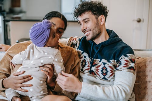 蓝色和白色连帽衫携带婴儿在白色和棕色奥尼的男人 · 免费素材图片