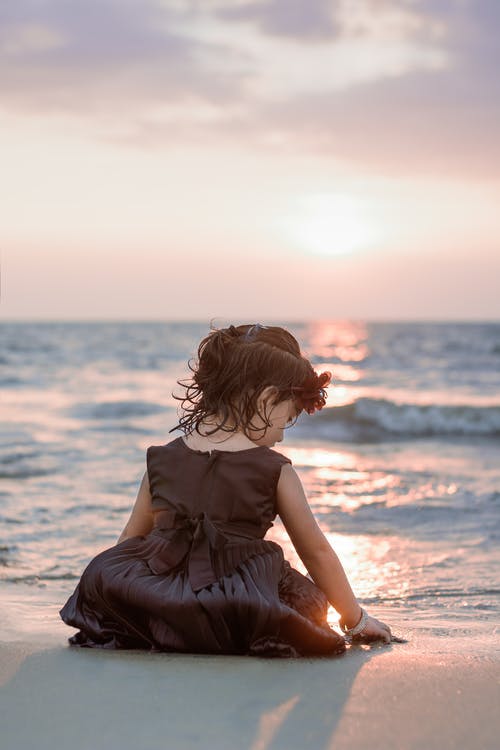 日落期间站在海滩上的棕色裙子的女孩 · 免费素材图片
