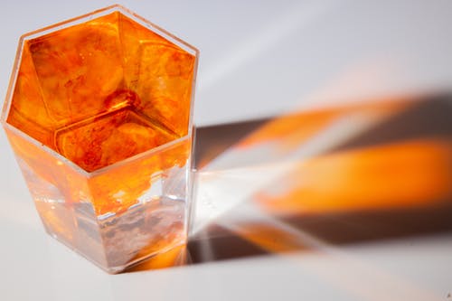 透明玻璃香水瓶，带橙色光 · 免费素材图片