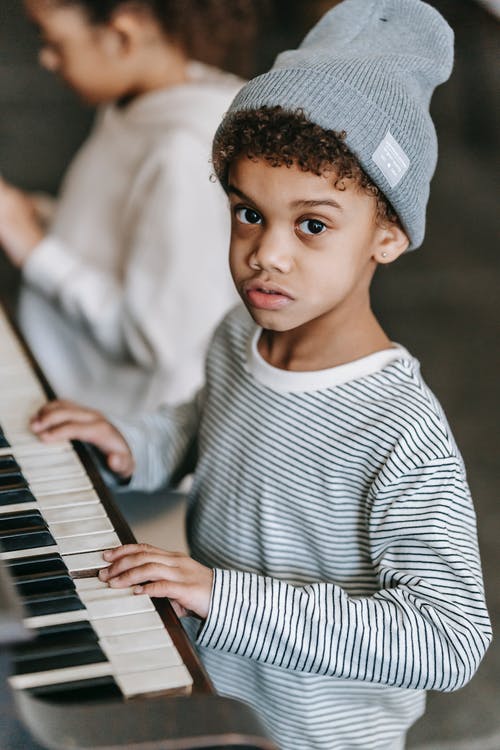 弹钢琴的白色和黑色条纹长袖衬衫的男孩 · 免费素材图片