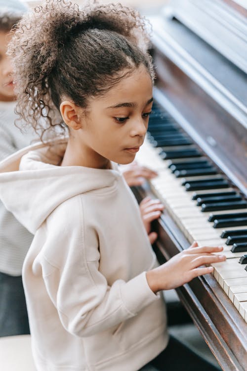 弹钢琴的米色外套的女人 · 免费素材图片