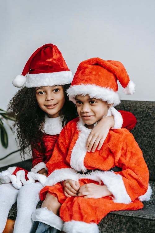 坐在圣诞老人服装的女孩旁边的红色和白色圣诞老人服装的女人 · 免费素材图片