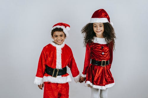 站在圣诞老人服装的女孩旁边的红色圣诞老人服装的女人 · 免费素材图片
