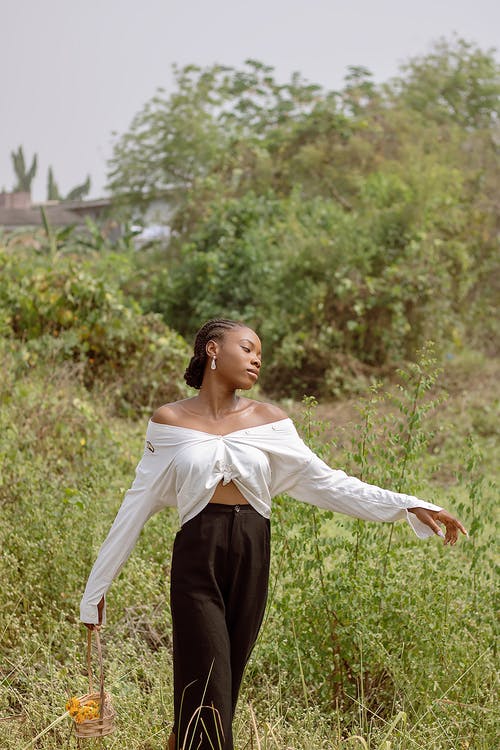 白色长袖衬衫和黑色的裤子，站在绿色的草地上的女人 · 免费素材图片