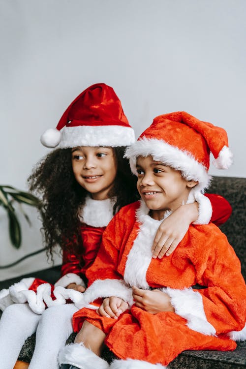 红色和白色圣诞老人服装携带婴儿在白色和红色圣诞老人帽子的女人 · 免费素材图片