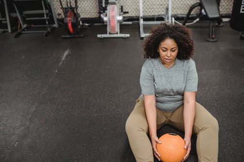 灰色的圆领t恤和棕色的短裤，坐在篮球场上的女人 · 免费素材图片