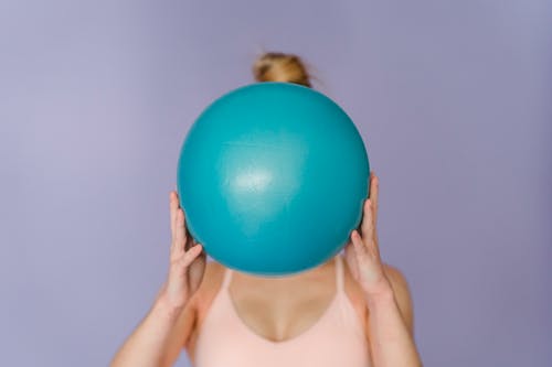拿着蓝色的球的白色背心的女人 · 免费素材图片