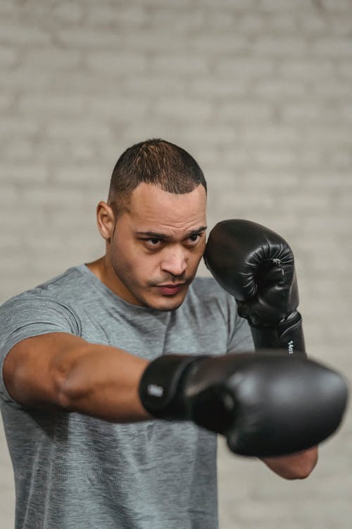 灰色乘员脖子上的t恤的男子戴着黑色拳击手套 · 免费素材图片
