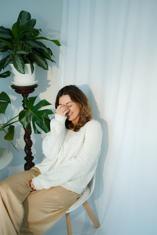 坐在棕色的沙发上的白毛衣的女人 · 免费素材图片