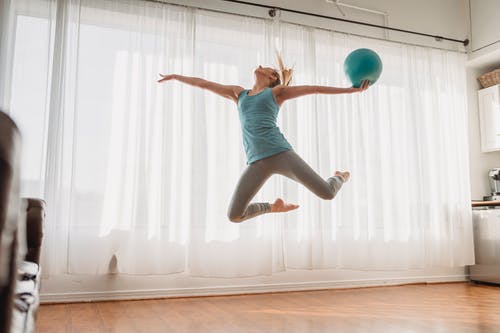 蓝色背心和空气中跳跃的灰色短裤的女人 · 免费素材图片