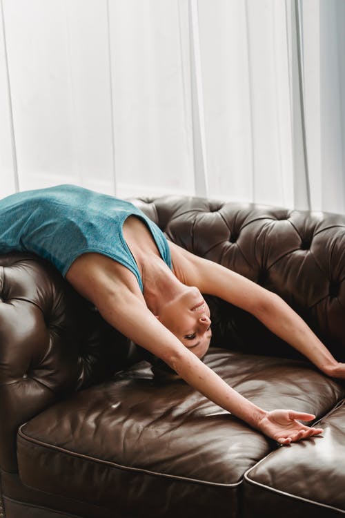 躺在棕色皮革沙发上的蓝色背心的女人 · 免费素材图片
