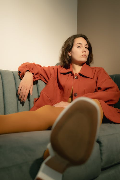 坐在灰色的沙发上的红色礼服衬衫的女人 · 免费素材图片