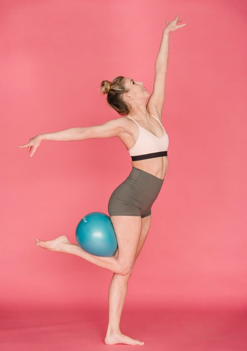 黑色运动胸罩和黑色短裤拿着蓝色运动球的女人 · 免费素材图片