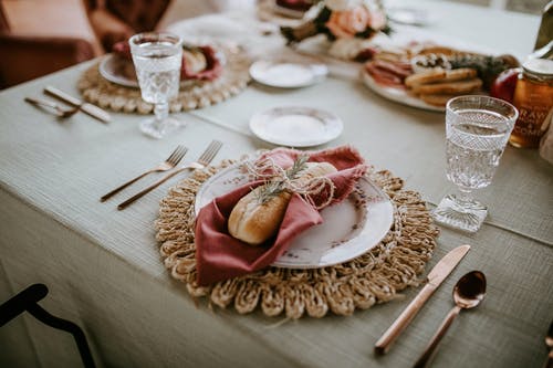 白色陶瓷板用不锈钢叉子和面包刀棕色木制的桌子上 · 免费素材图片