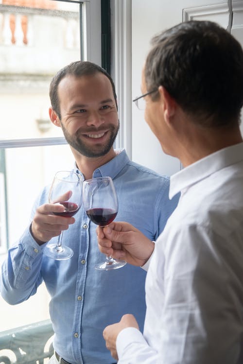两个男人用红酒碰杯相望 · 免费素材图片