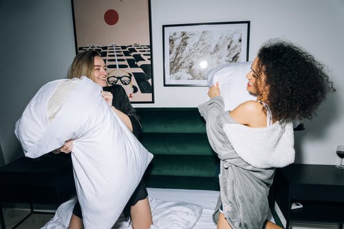 两名年轻妇女开心做枕头大战 · 免费素材图片